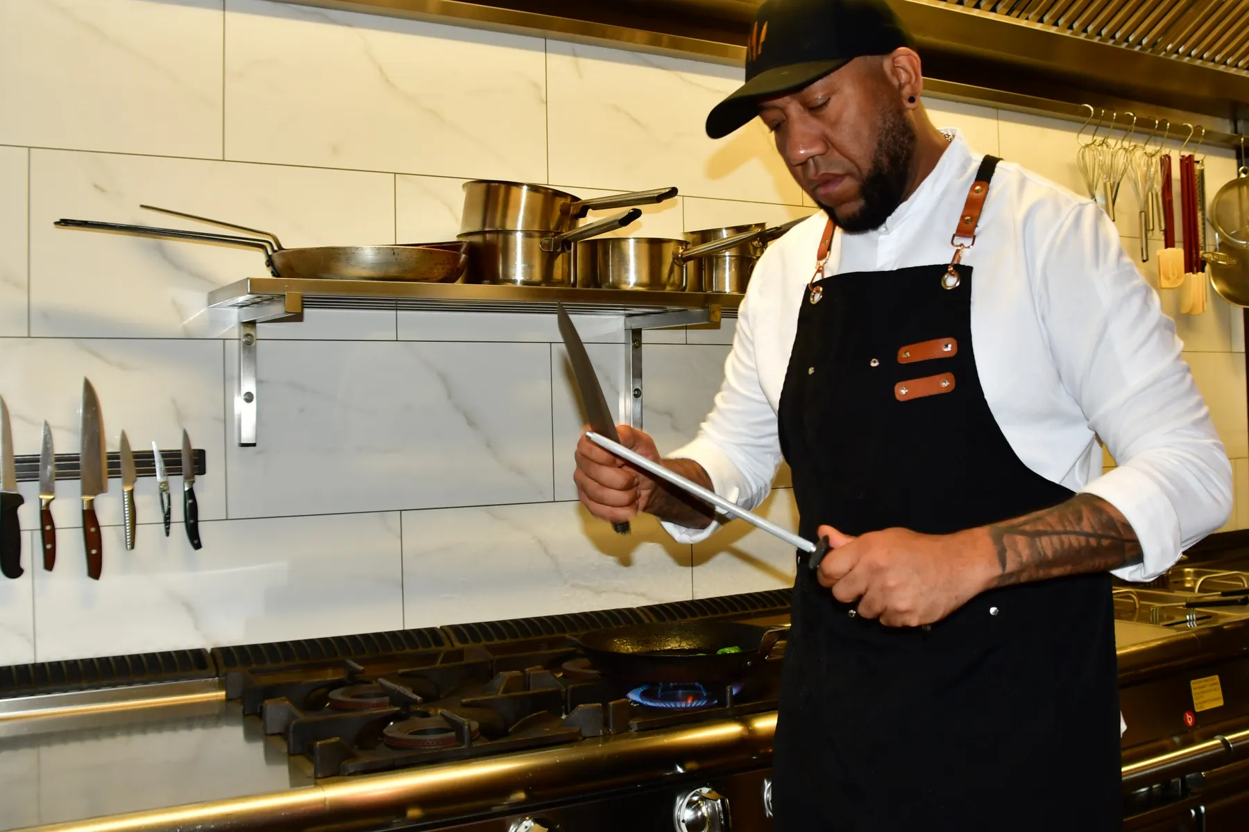 Chef Wilmar Raphaela honing a knife in the kitchen